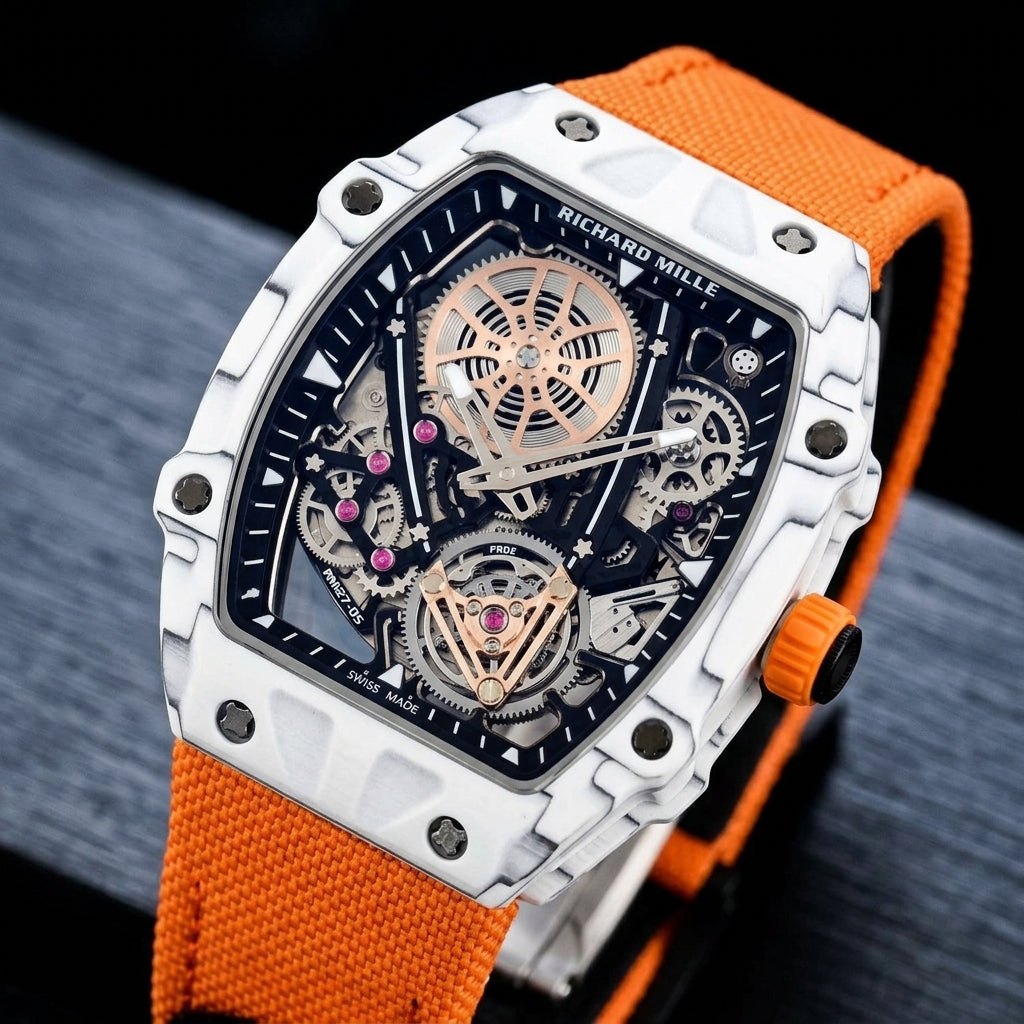 White carbon skeleton watch at a three-quarter angle on dark slate, its ribbed orange crown beside the curved case