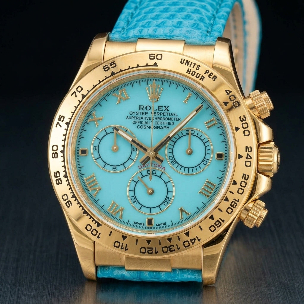Gold-tone chronograph at a three-quarter angle on dark slate, its screw-down crown and fluted pushers beside a turquoise lizard-grain strap
