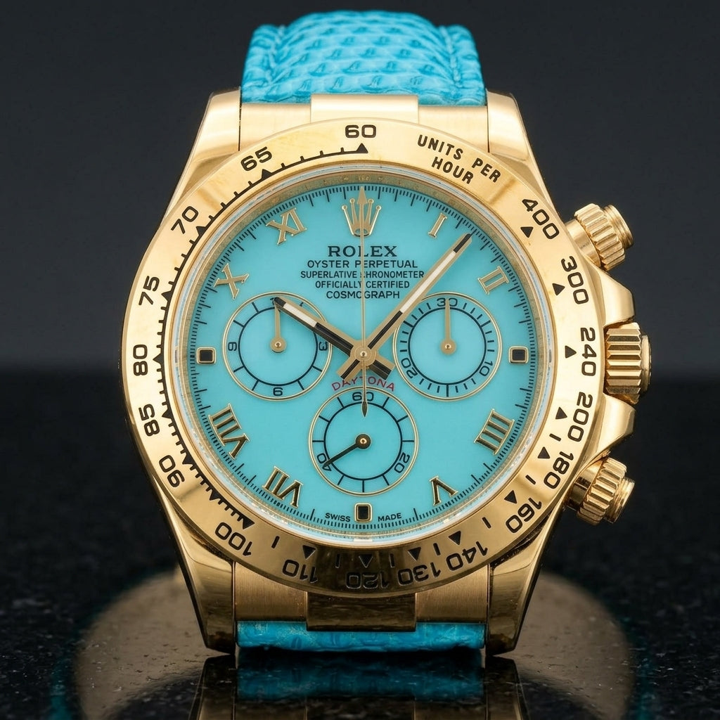 Gold-tone chronograph with a turquoise dial on a turquoise lizard-grain strap, worn on the wrist below a navy suit cuff