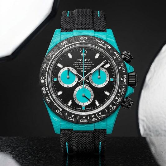 Turquoise-cased chronograph with a forged-carbon bezel and black dial on pale stone