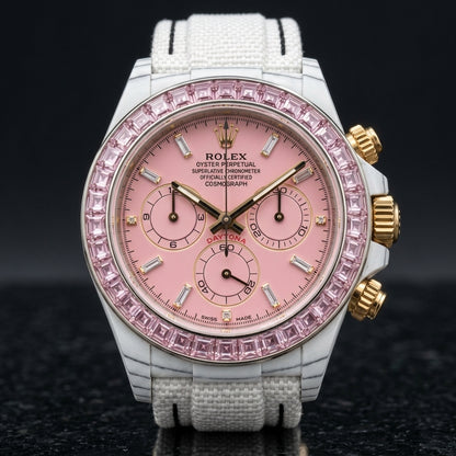 White carbon chronograph with a pale pink stone bezel on its white woven strap, worn on the wrist below a cream sleeve