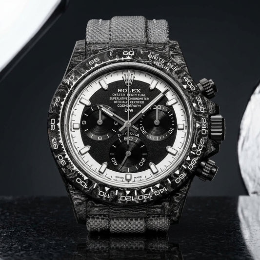 Forged-carbon chronograph with a black dial inside a white chapter ring, on pale stone