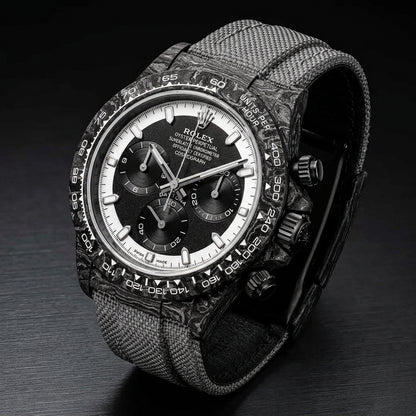 Forged-carbon chronograph at a three-quarter angle on dark slate, grey woven strap