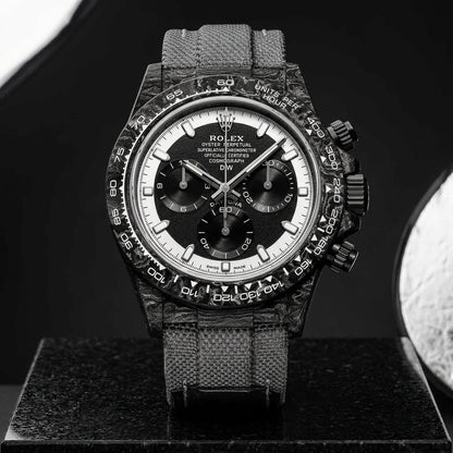 Forged-carbon chronograph on a grey woven strap, worn under a cuff