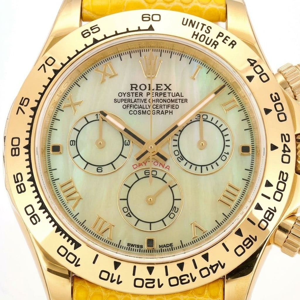 Macro of the pale yellow mother-of-pearl dial, its gold Roman numerals, three yellow counters ringed in gold and the black tachymeter scale