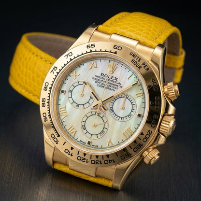 Gold-tone chronograph with a yellow mother-of-pearl dial on a bright yellow lizard-grain strap, worn on the wrist below a navy suit cuff